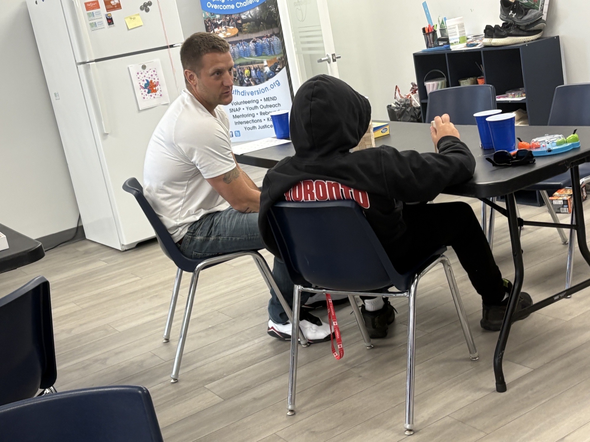 C.O.S.M.O. facilitator speaking one-on-one with a youth participant seen from behind